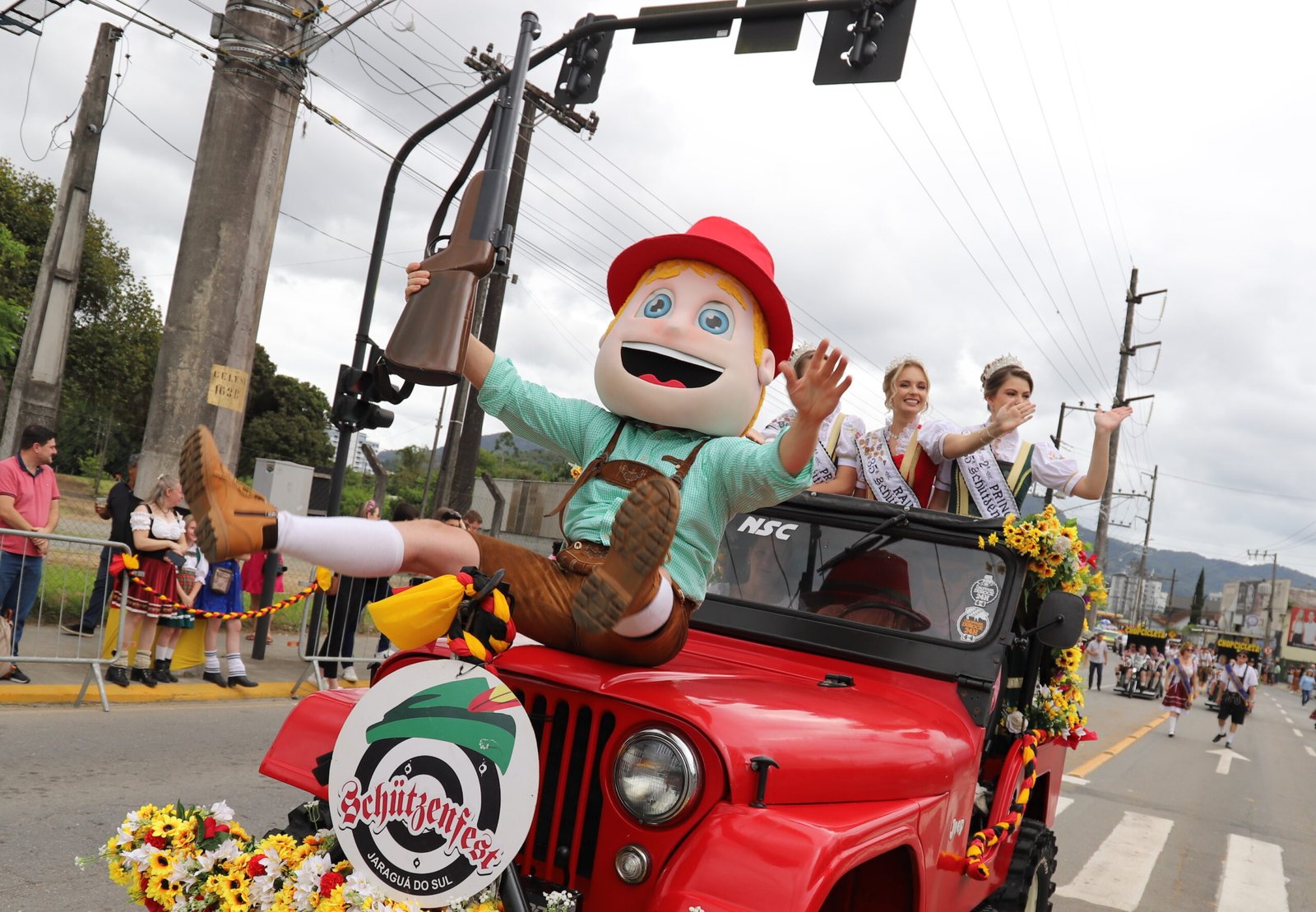 Mascote e rainhas da Schützenfest desfilam em carro aberto decorado.