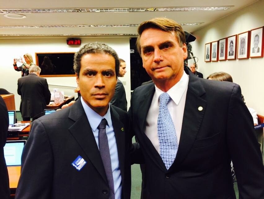 Demetrius Oliveira posa ao lado de Jair Bolsonaro em ambiente institucional.