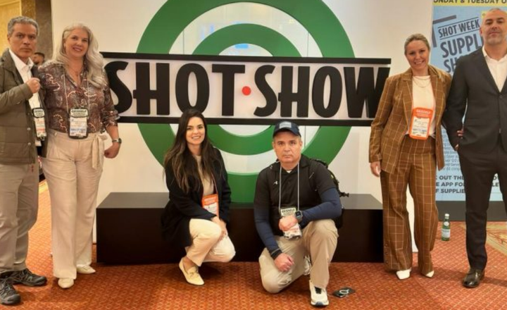Grupo da Triggers Magazine posa diante do letreiro da Shot Show.