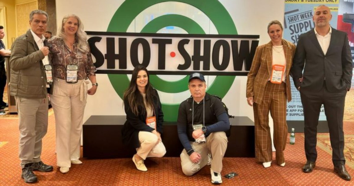 Grupo da Triggers Magazine posa diante do letreiro da Shot Show.