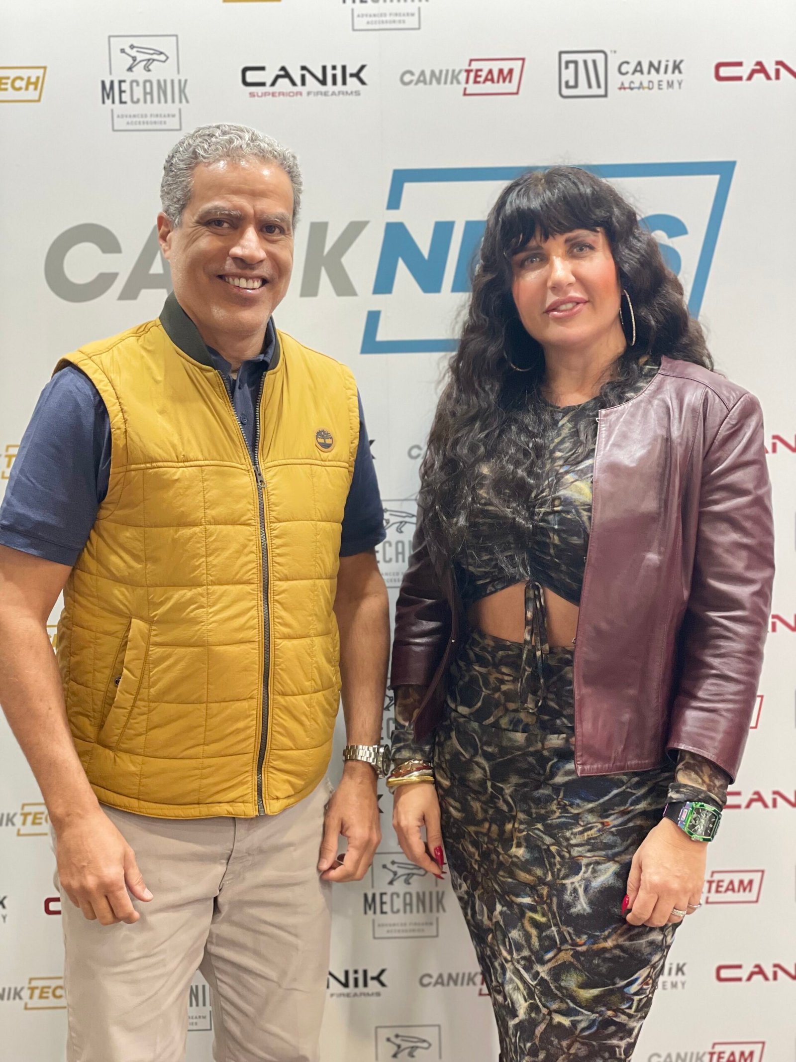 Demetrius Oliveira posa com representante da Canik em estande da marca.