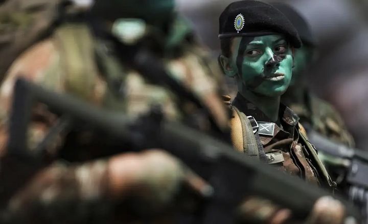 Militar mulher usando boina e camuflagem durante formação.