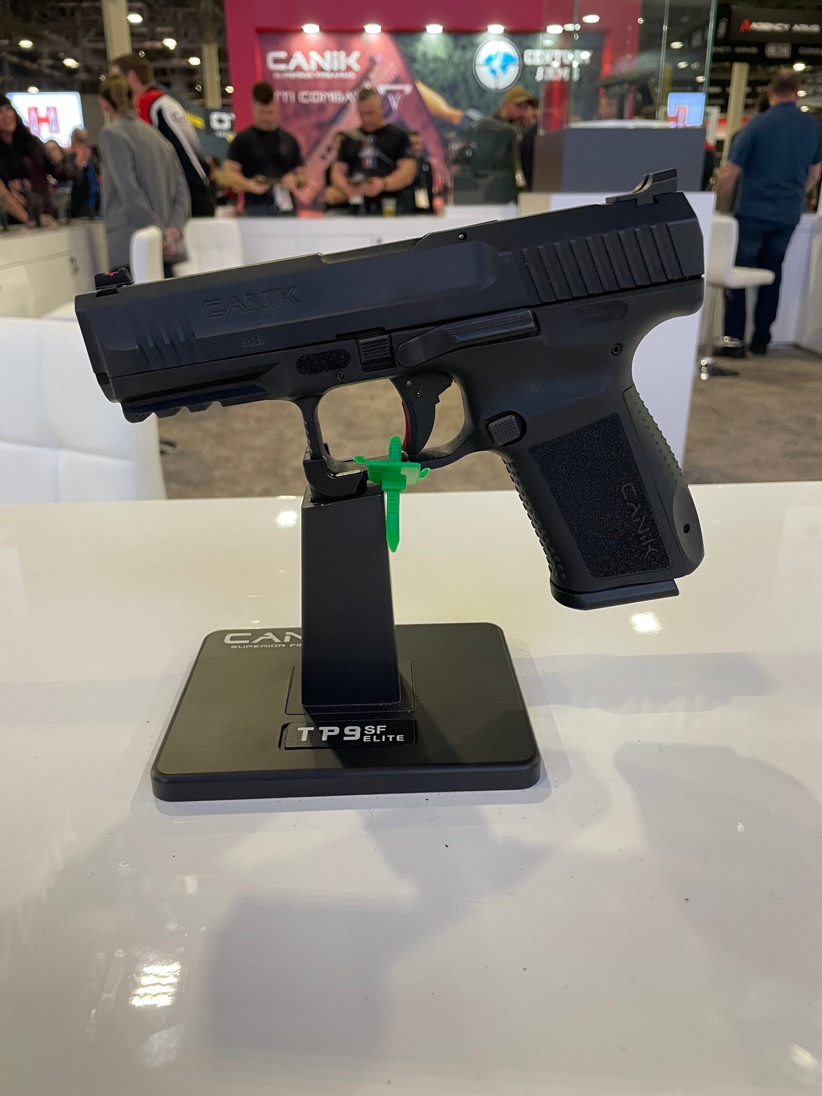 Pistola Canik exposta em suporte durante feira do setor.
