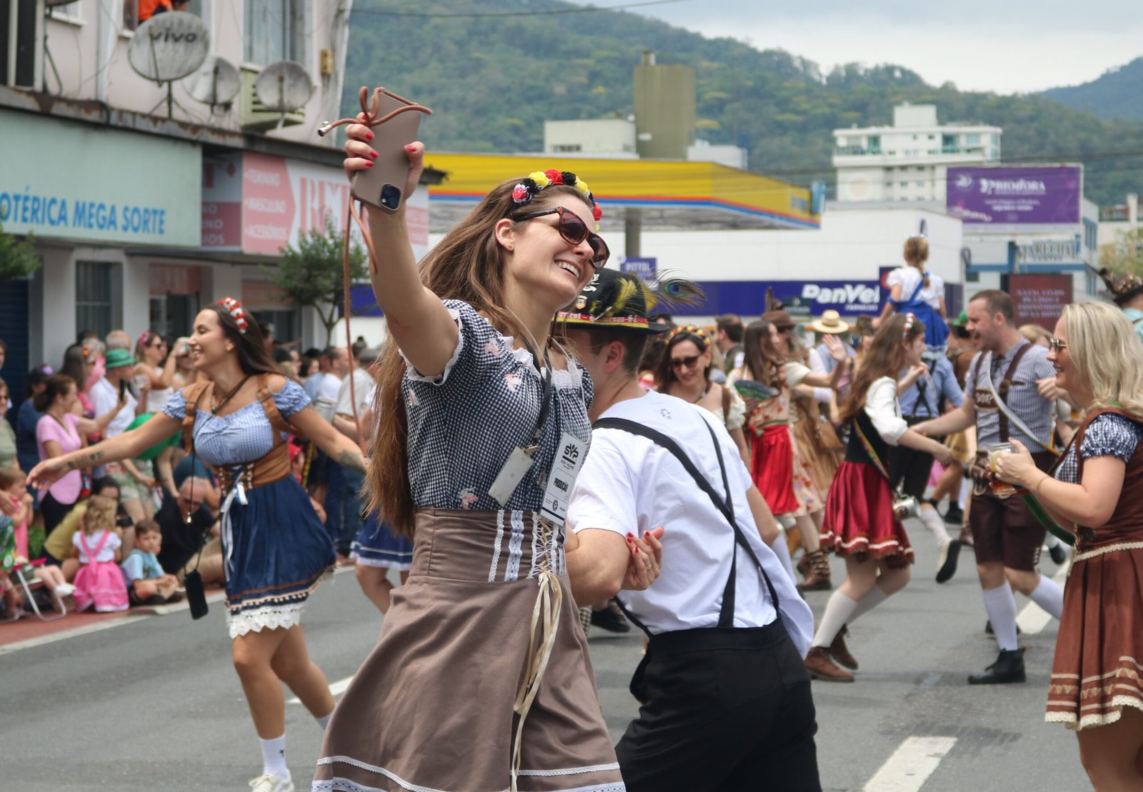 Mulher em traje típico registra selfie durante desfile da Schützenfest.