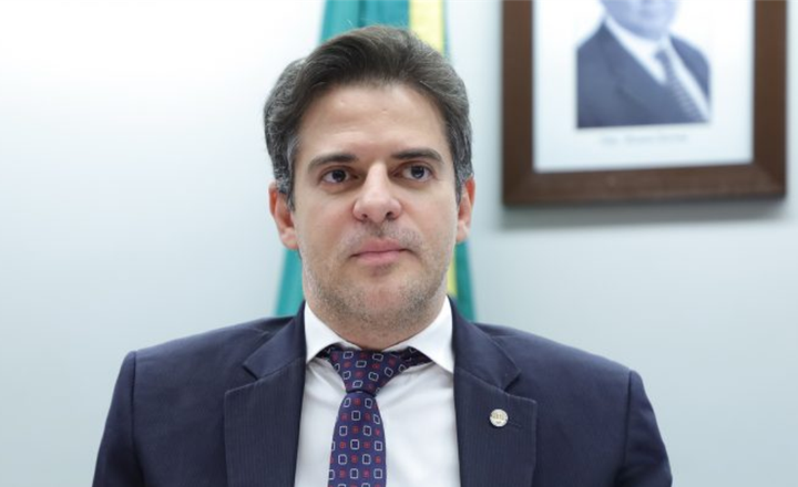 Deputado posa de terno em ambiente institucional.