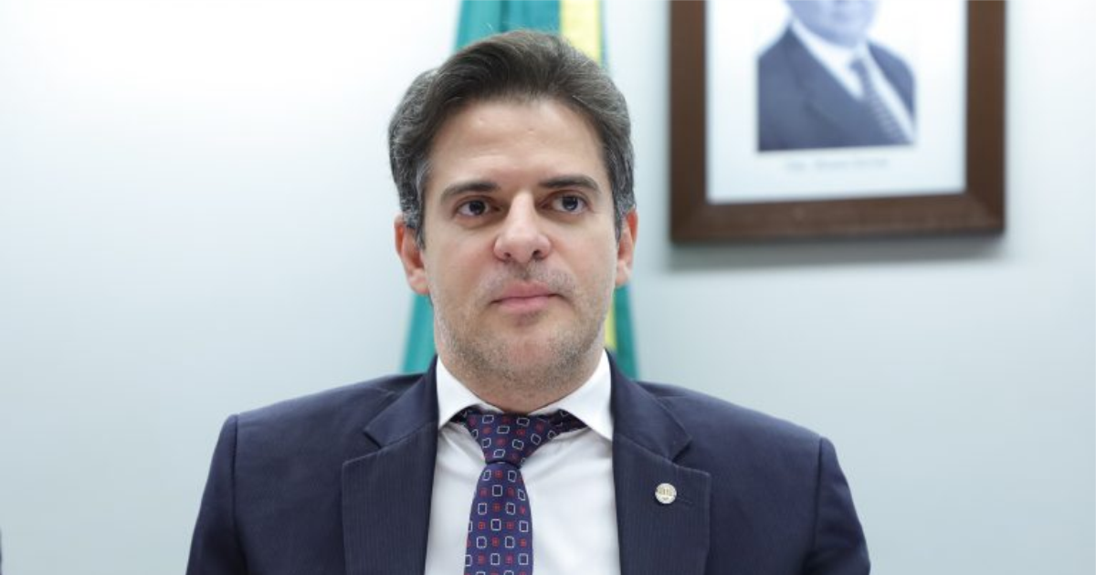 Deputado posa de terno em ambiente institucional.