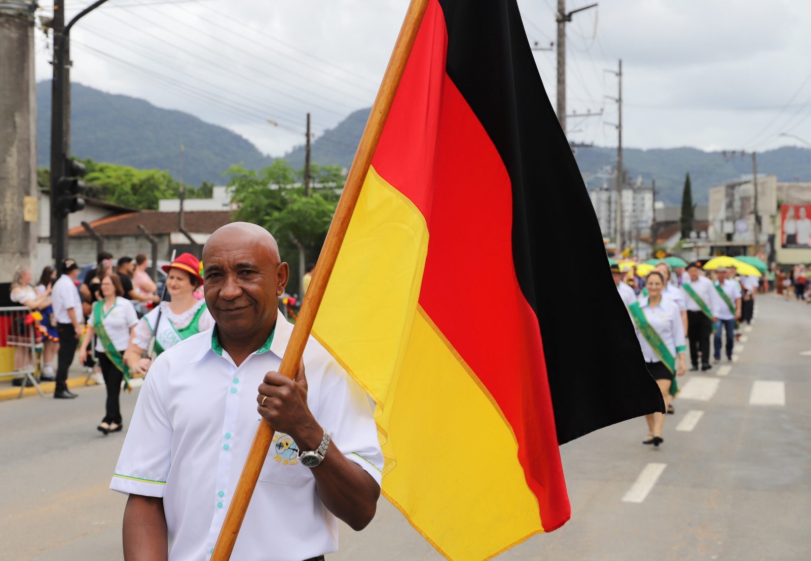 Homem carrega bandeira da Alemanha durante desfile da Schützenfest.