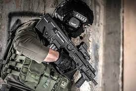 Operador tático segura fuzil IWI Tavor X95 em ambiente urbano.
