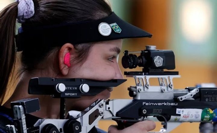 Atleta brasileira mira uma carabina em prova olímpica.
