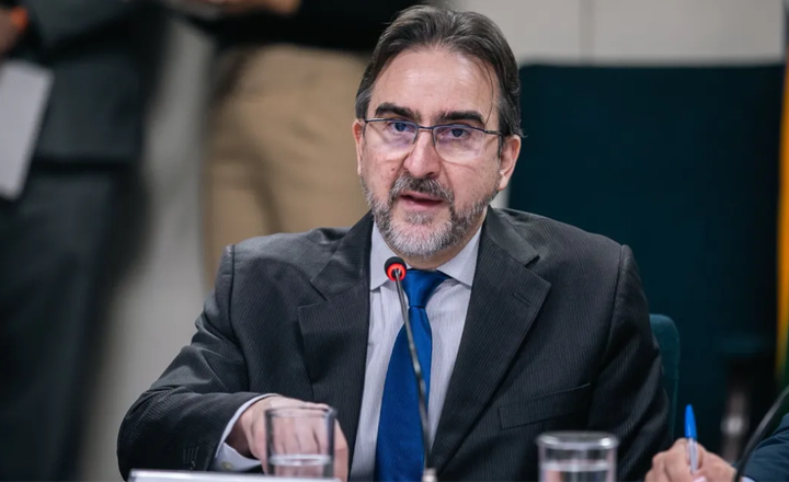 Bernard Appy fala ao microfone durante reunião oficial.