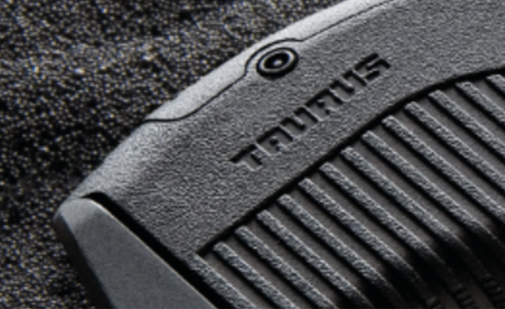 Detalhe do ferrolho de uma pistola Taurus com gotas de água.