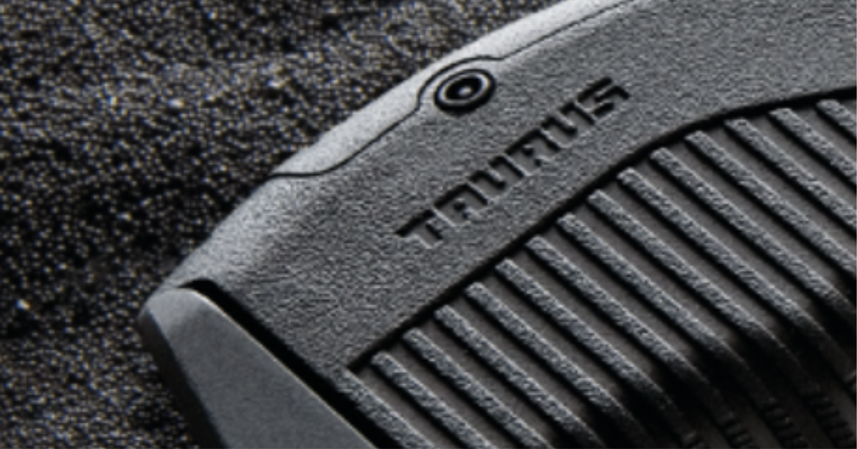 Detalhe do ferrolho de uma pistola Taurus com gotas de água.