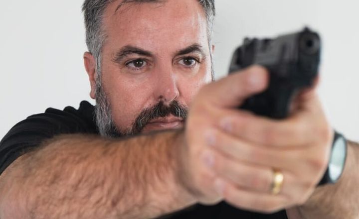 Homem demonstra equipamento de visão segurando uma pistola.