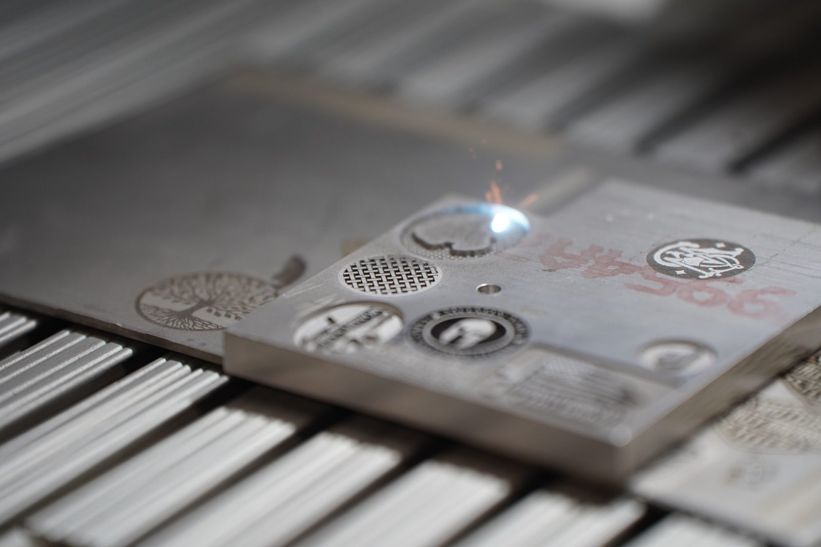 Placa metálica gravada é exibida sobre equipamento de personalização.