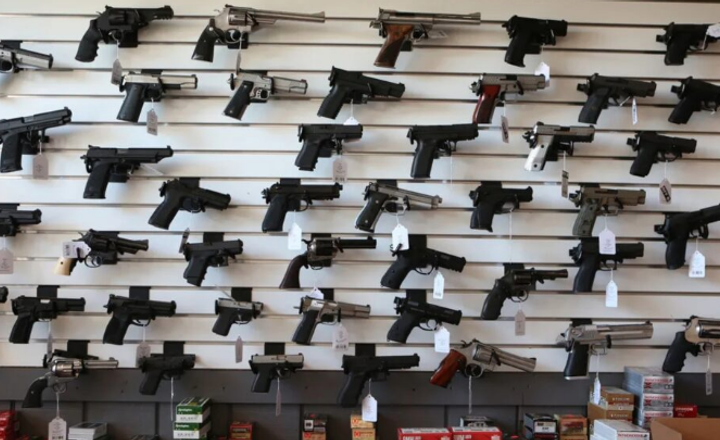 Diversas pistolas expostas em painel de loja de armas.