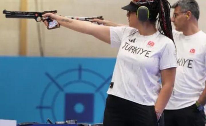 Atleta turca aponta uma pistola durante prova de tiro esportivo.