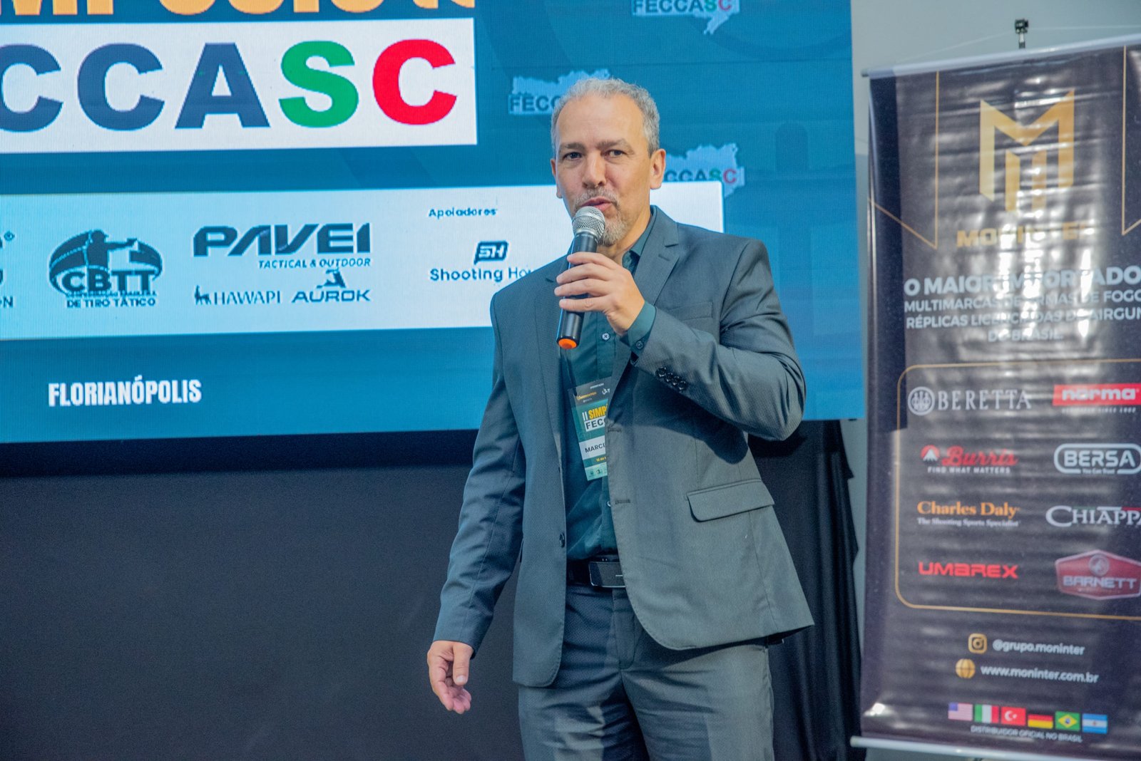 Homem de terno apresenta palestra no Simpósio FECCASC 2025.