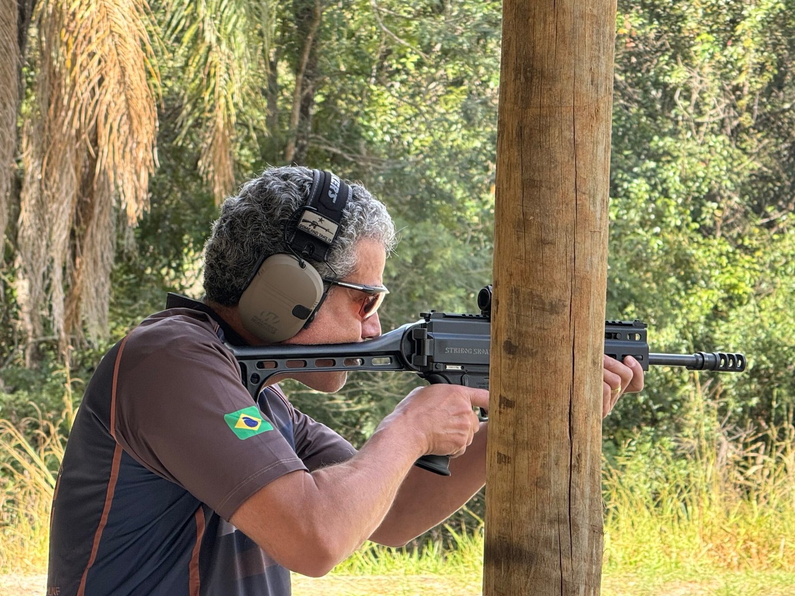 Demetrius Oliveira dispara arma longa em campo de tiro ao ar livre.