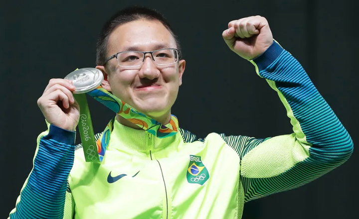 Atleta brasileiro exibe medalha de prata olímpica e comemora.