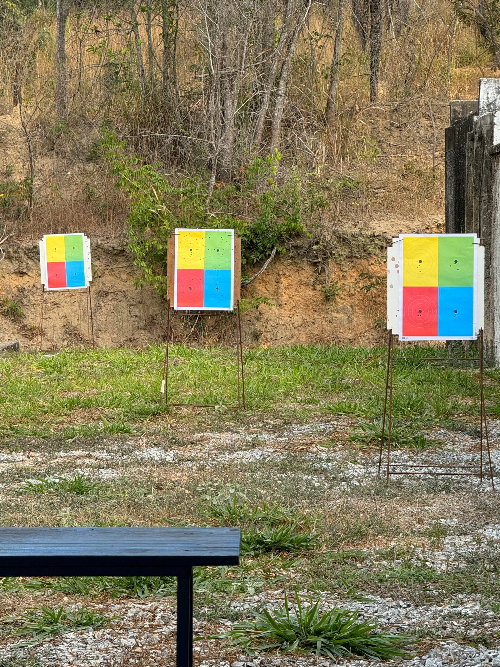 Alvos coloridos alinhados em pista de tiro ao ar livre.