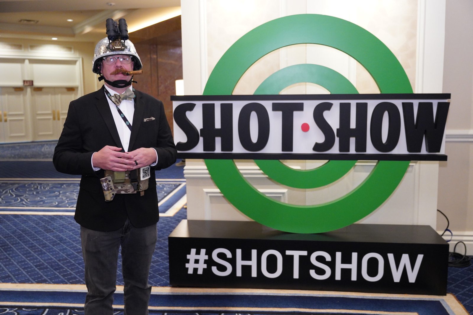 Participante posa diante do grande logotipo da Shot Show.