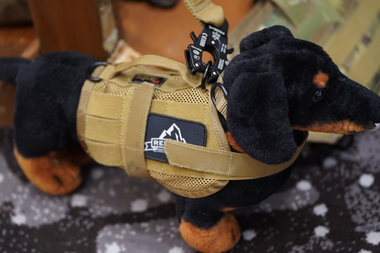 Miniatura de cão usa colete tático em exposição de acessórios.