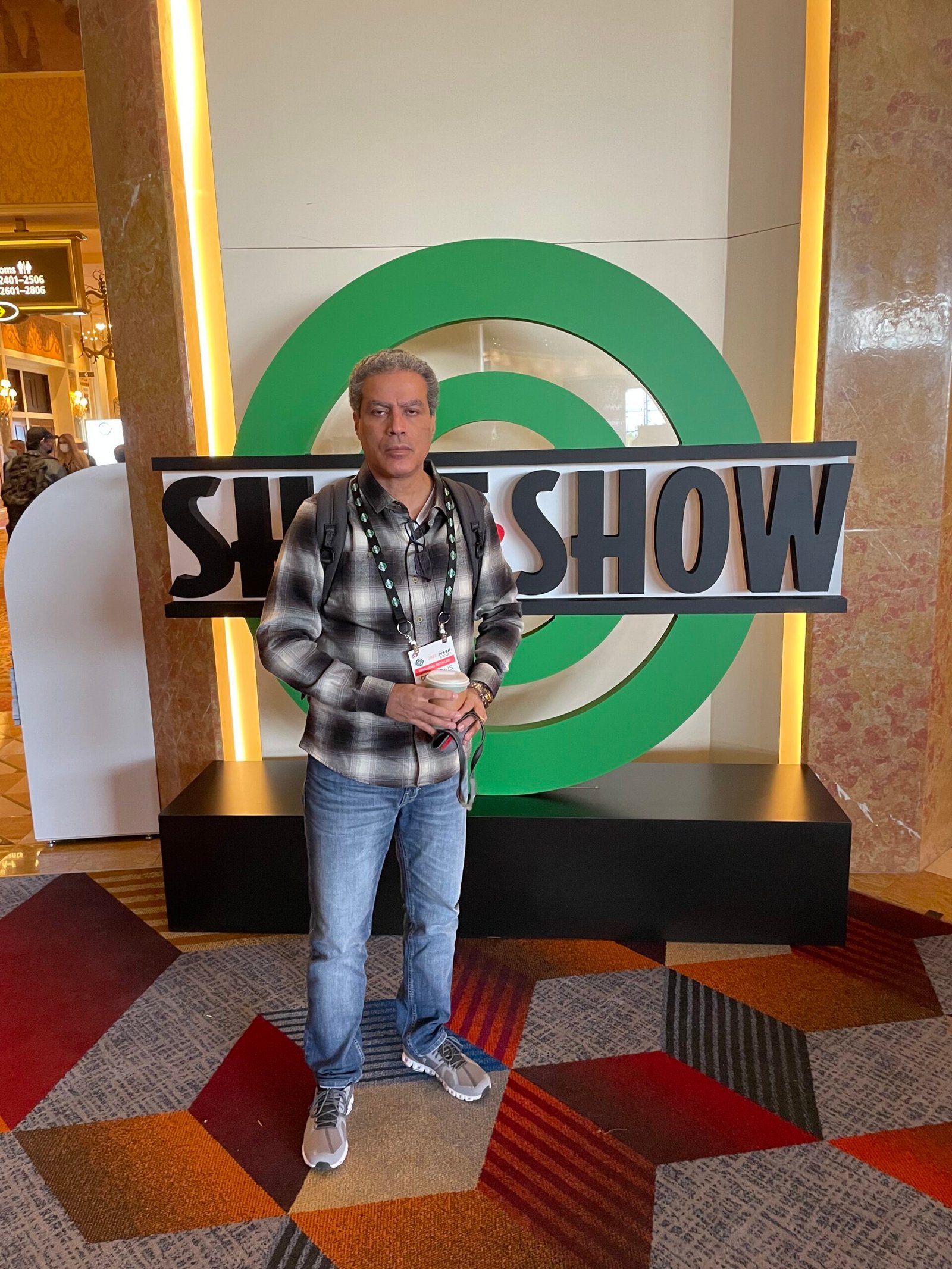 Participante posa diante do logotipo da Shot Show.