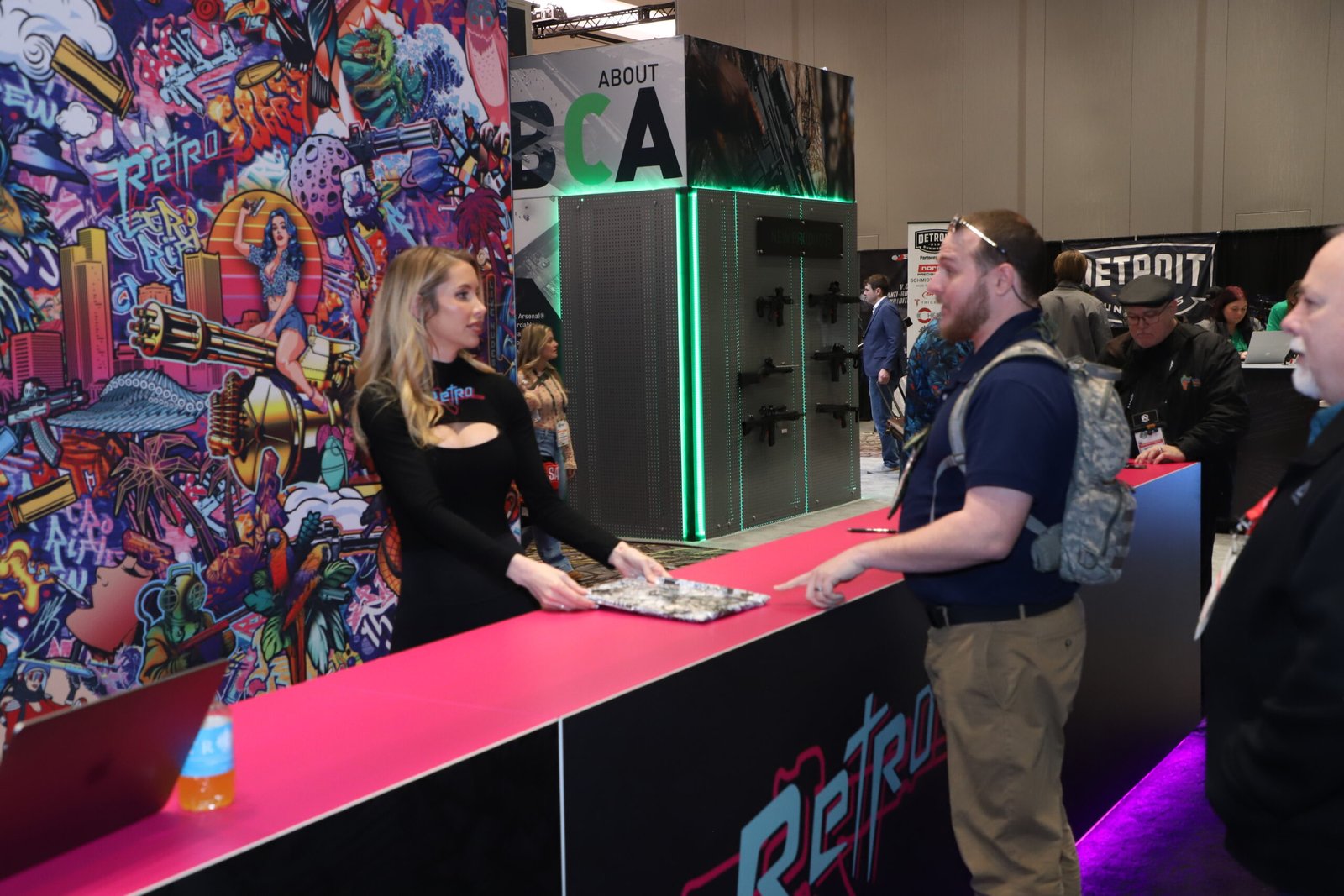 Expositora conversa com visitante em estande colorido da Shot Show.