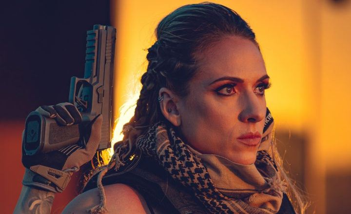 Ilustração de mulher segurando uma pistola em ambiente iluminado em tons alaranjados.