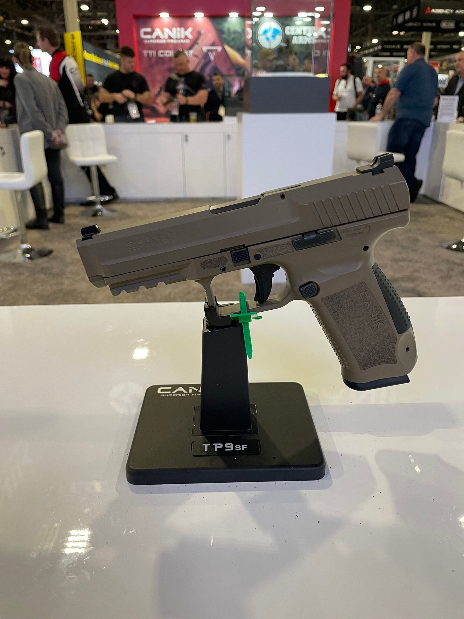 Pistola Canik exposta em suporte durante feira do setor.