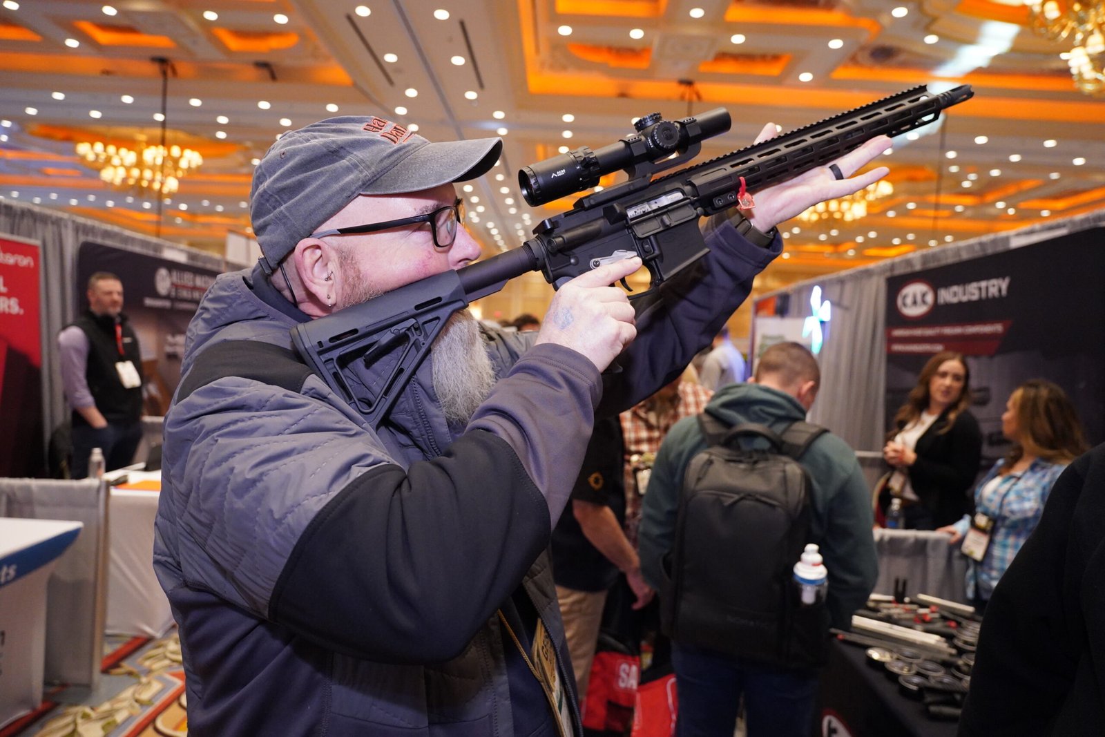 Visitante testa carabina equipada com mira dentro de estande da Shot Show.