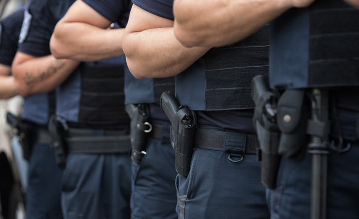Fileira de policiais armados durante formação em área pública.