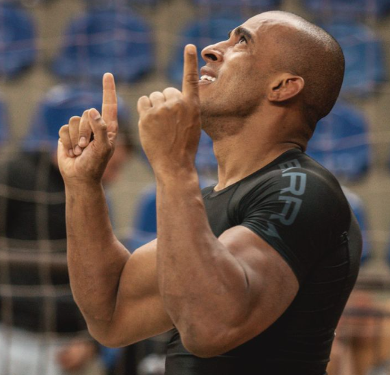 Léo Rocha comemora apontando para o alto durante competição de jiu-jítsu.