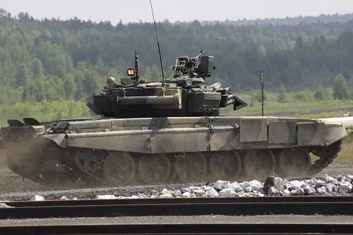 Tanque militar percorre terreno aberto durante exercício.