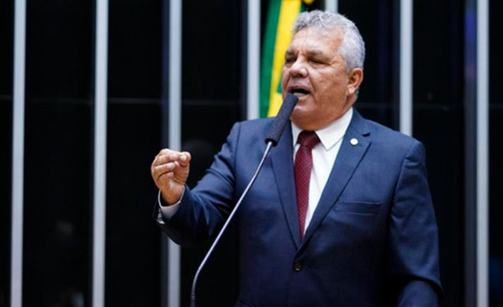 Deputado Alberto Fraga discursa em plenário com a bandeira do Brasil ao fundo.