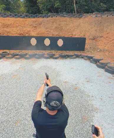 Atirador visto de cima aponta pistola para sequência de alvos de papel.