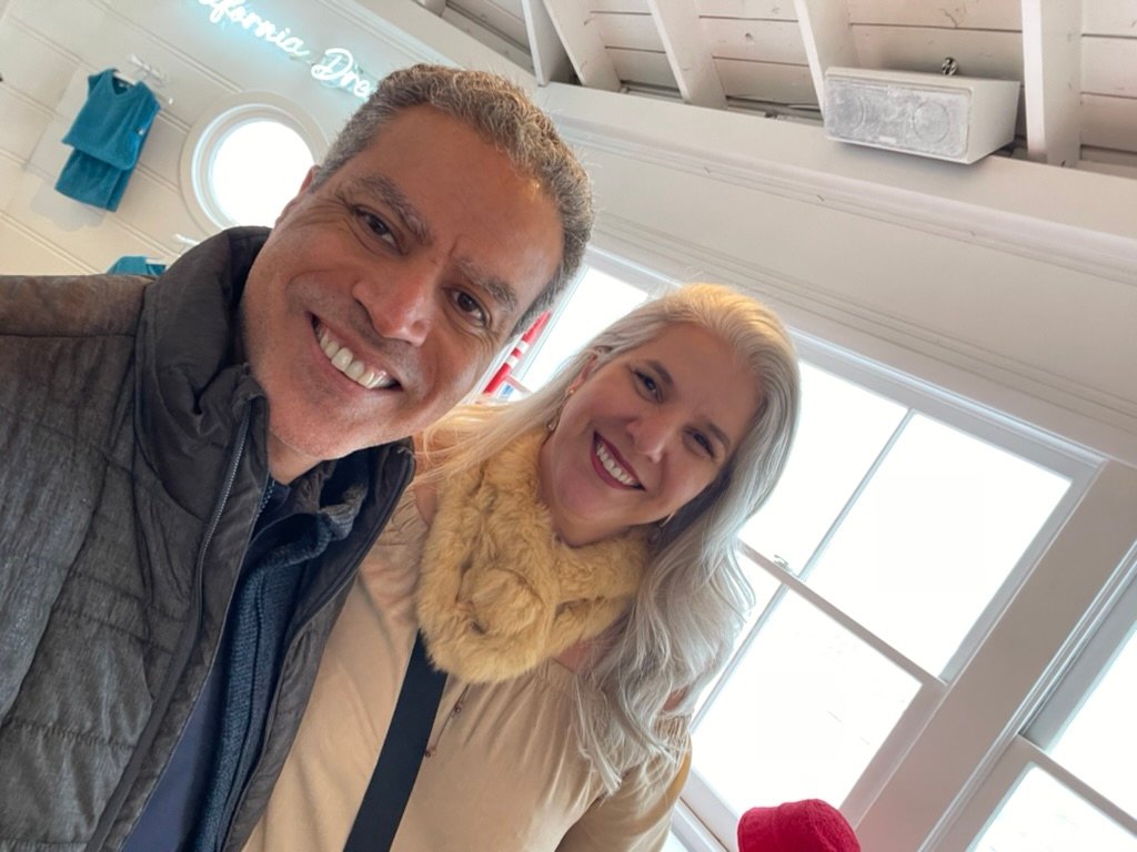 Demetrius Oliveira e uma mulher tiram selfie em ambiente interno.
