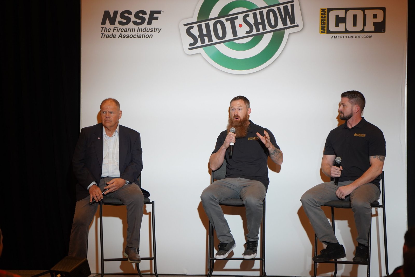 Três palestrantes conversam no palco durante sessão da Shot Show.