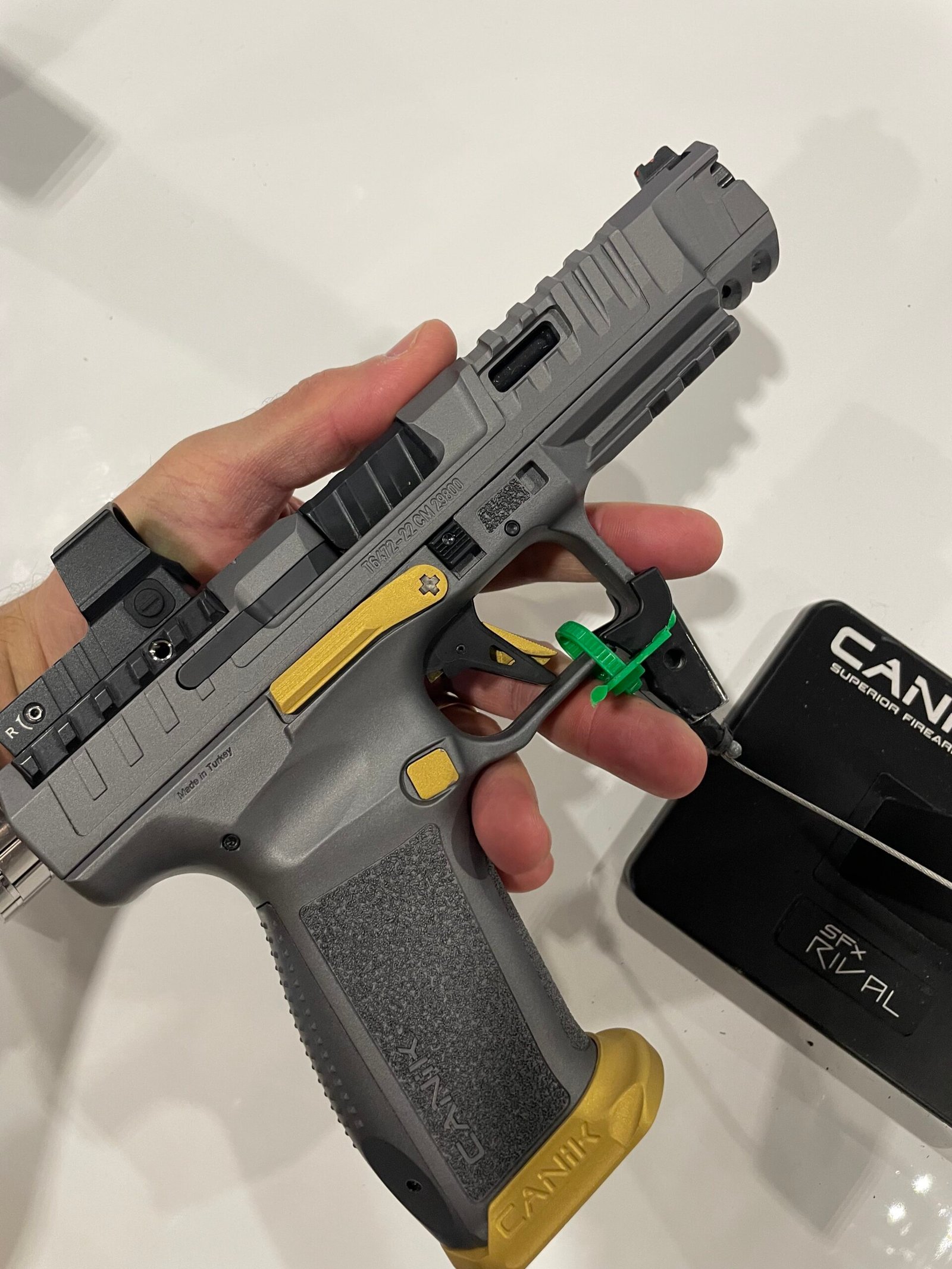 Detalhes de pistolas Canik expostas em suporte durante feira.