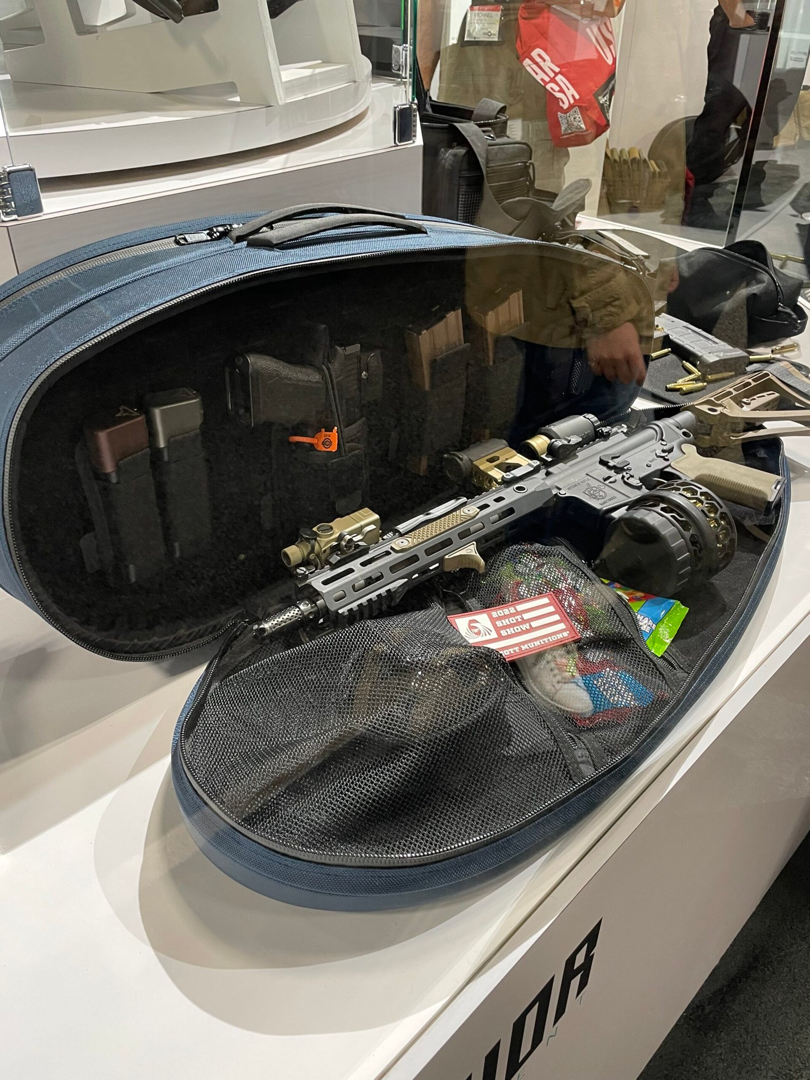 Estojo oval aberto com arma e acessórios em exposição.