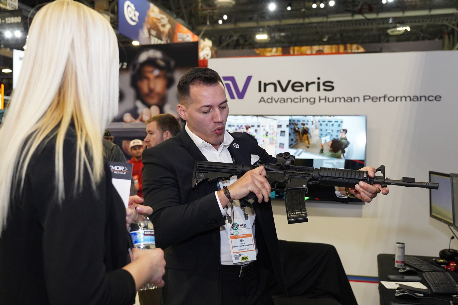 Expositor demonstra fuzil a uma visitante na Shot Show.