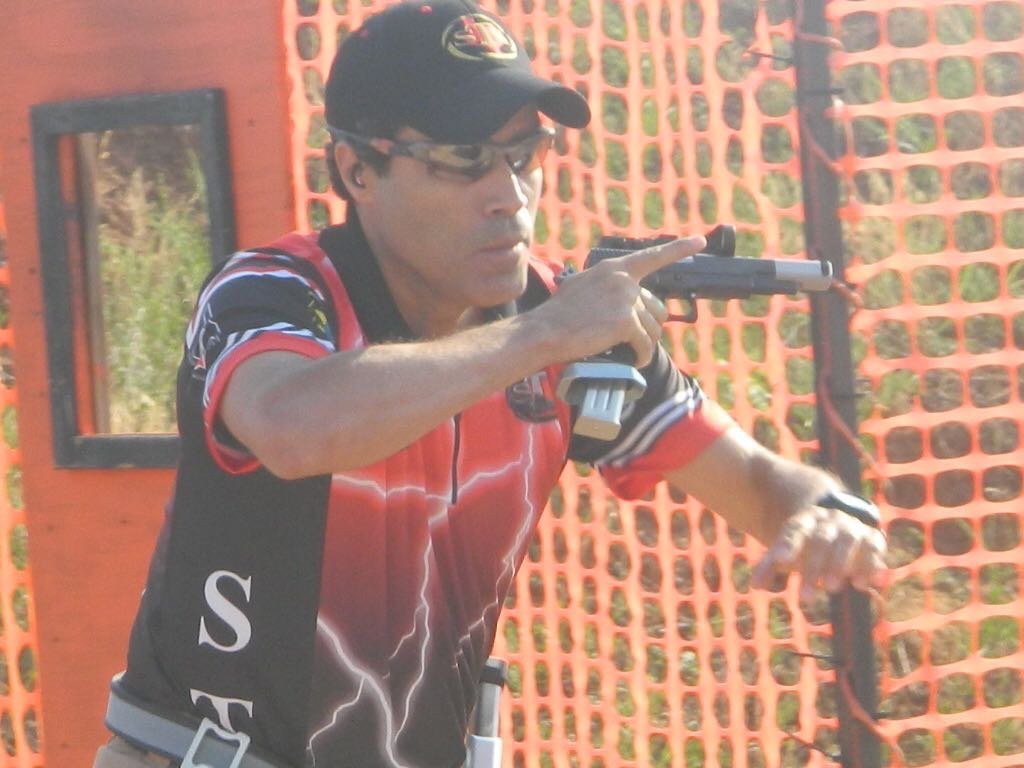 Demetrius Oliveira percorre uma pista de tiro prático com pistola.