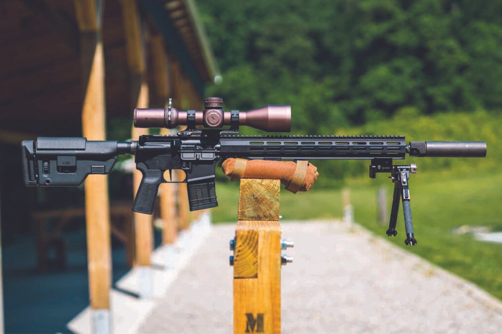 Fuzil IWI Zion-15 equipado com mira e apoiado em suporte de madeira.