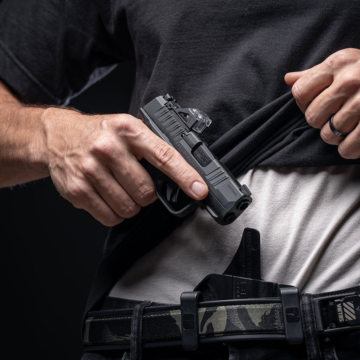 Pessoa retira pistola Springfield Armory Hellcat de coldre na cintura.