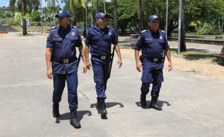 Três guardas municipais caminham em uma praça pública do Recife.