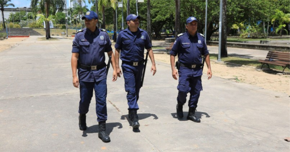 Três guardas municipais caminham em uma praça pública do Recife.