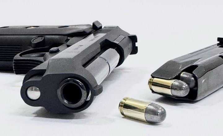 Duas pistolas e munição sobre fundo branco.