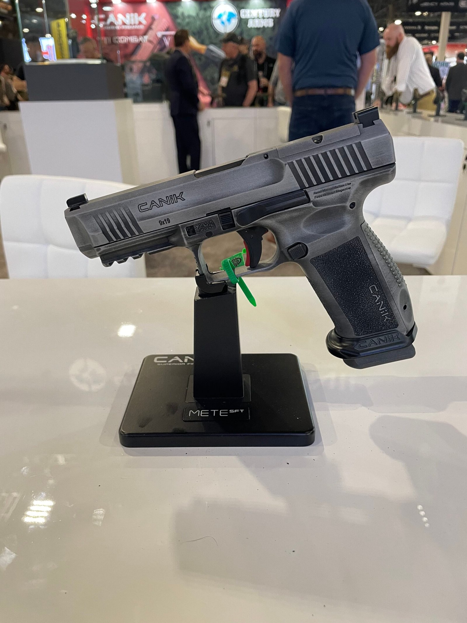 Pistola Canik exposta em suporte durante feira do setor.