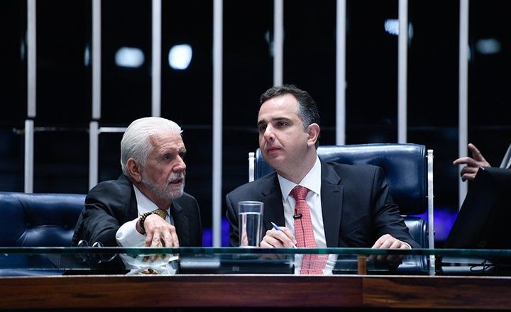 Dois senadores conversam à mesa diretora do plenário.