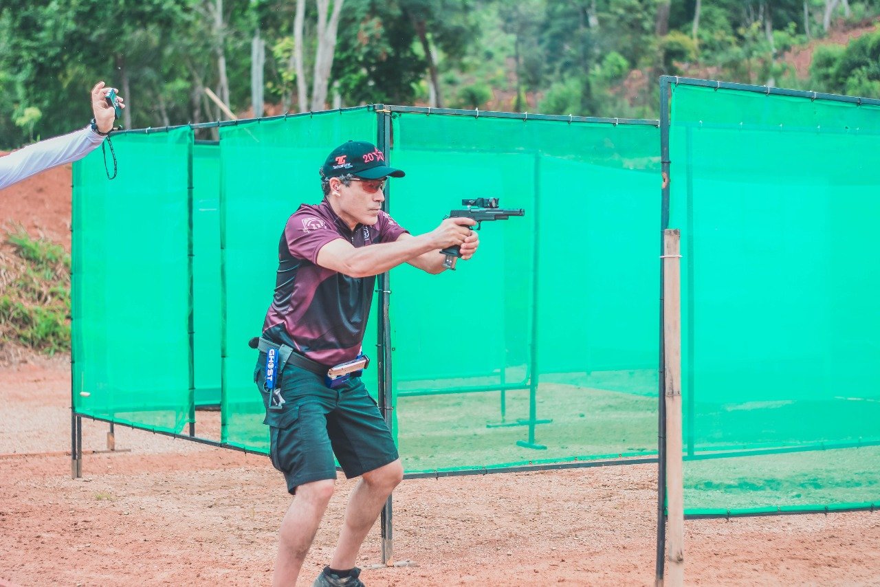 Demetrius Oliveira dispara pistola durante prova de tiro prático.